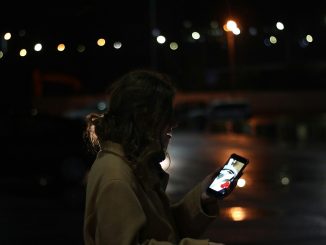 Close-up of woman holding phone in blurred urban background