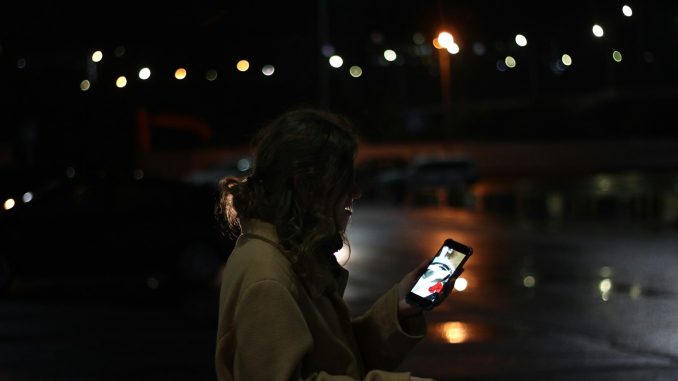 Close-up of woman holding phone in blurred urban background